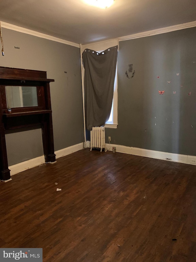 empty room featuring dark hardwood / wood-style flooring, crown molding, and radiator