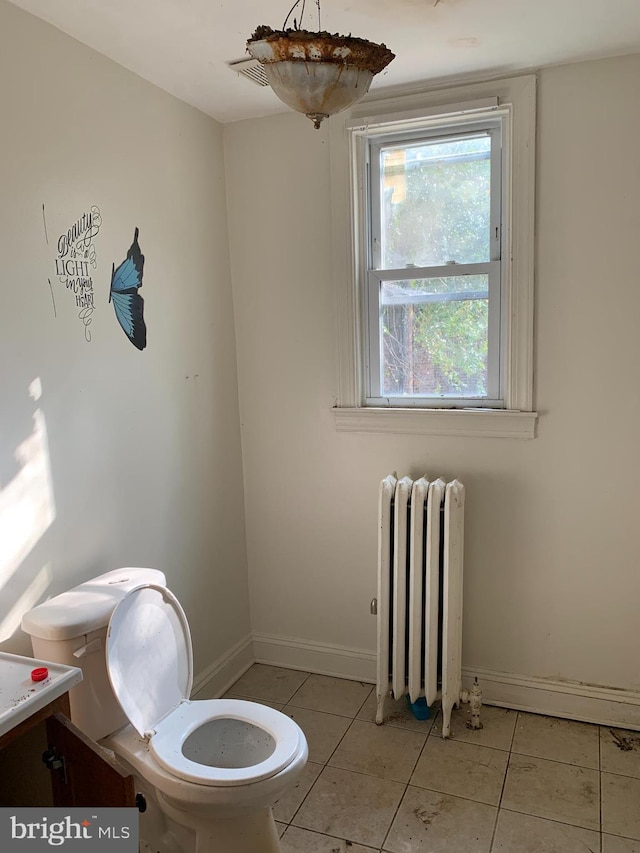 bathroom featuring tile flooring, vanity, toilet, and radiator heating unit