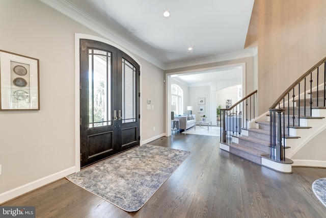 foyer featuring dark hardwood / wood-style flooring, a wealth of natural light, ornamental molding, and french doors