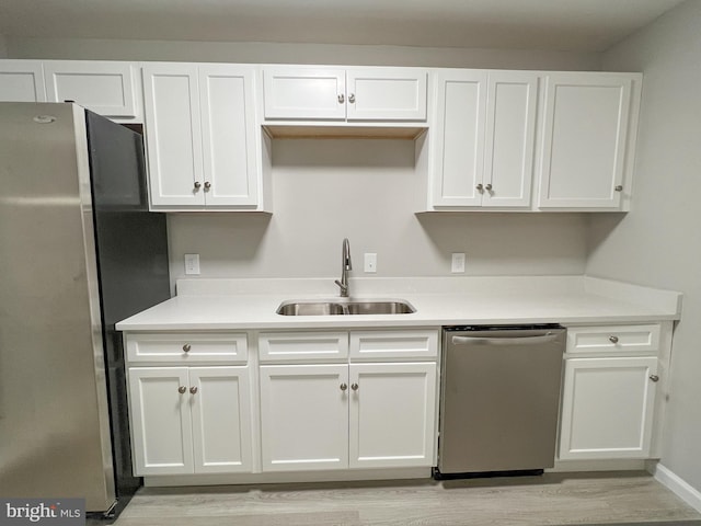 kitchen with sink, light hardwood / wood-style flooring, appliances with stainless steel finishes, and white cabinetry