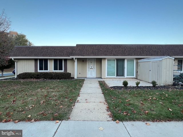 ranch-style house featuring a storage shed and a front yard