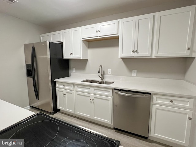 kitchen with white cabinetry, light wood-type flooring, appliances with stainless steel finishes, and sink