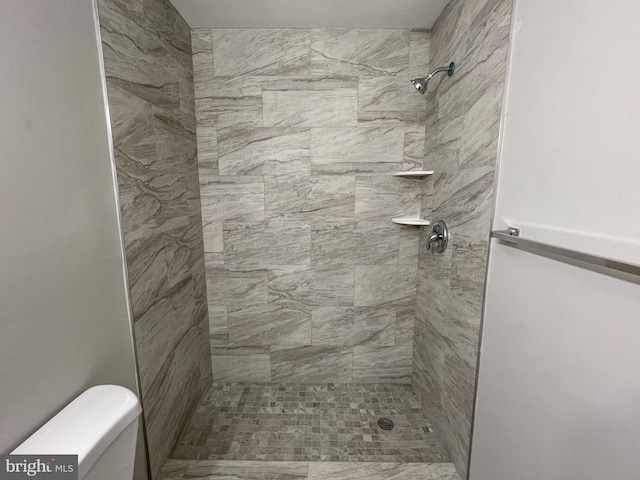 bathroom featuring toilet and a tile shower