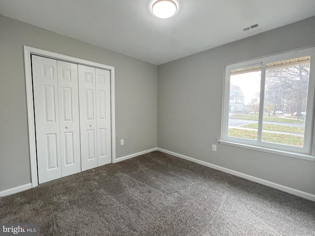 unfurnished bedroom featuring dark carpet and a closet