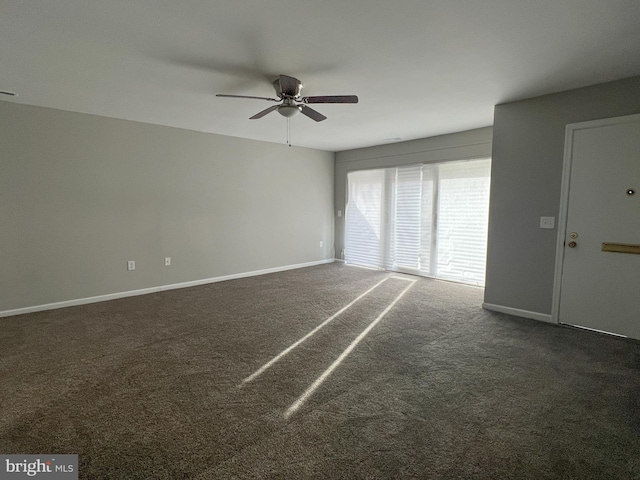 spare room featuring dark colored carpet and ceiling fan