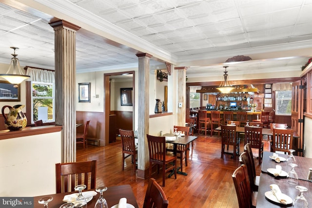 dining area with crown molding, dark hardwood / wood-style floors, and ornate columns