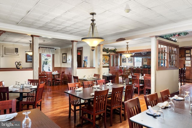 dining space featuring crown molding, decorative columns, wood-type flooring, and a wealth of natural light