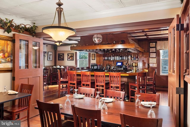 dining area featuring ornamental molding, indoor bar, and hardwood / wood-style flooring