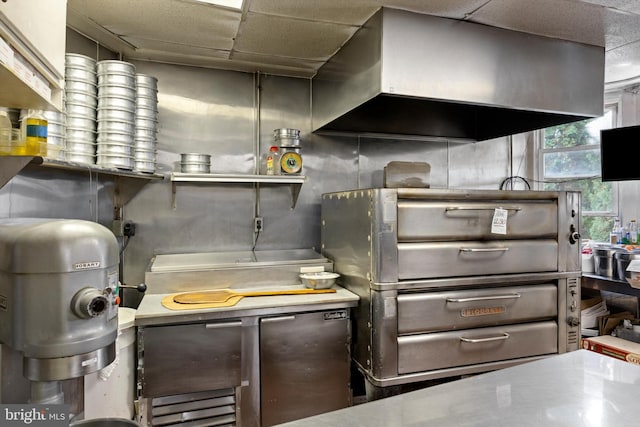 interior space with wall chimney exhaust hood and a drop ceiling