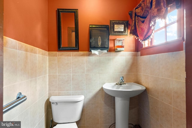 bathroom featuring tile walls, toilet, and sink