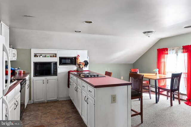 kitchen featuring dark tile flooring, white cabinetry, a breakfast bar area, lofted ceiling, and black appliances