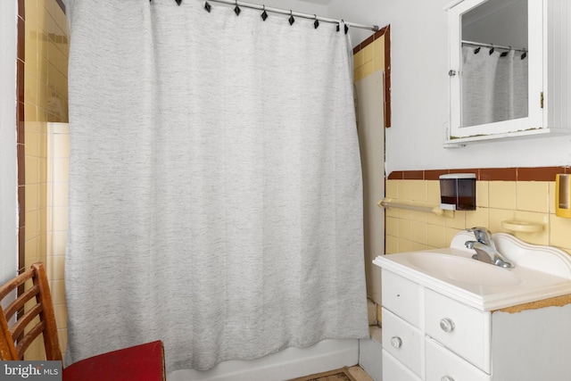 bathroom featuring tile walls, backsplash, large vanity, and shower / tub combo