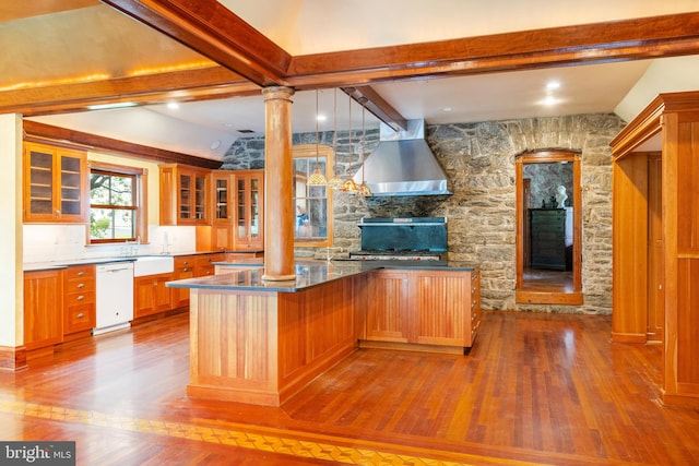 kitchen featuring light hardwood / wood-style floors, decorative columns, wall chimney range hood, beam ceiling, and white dishwasher