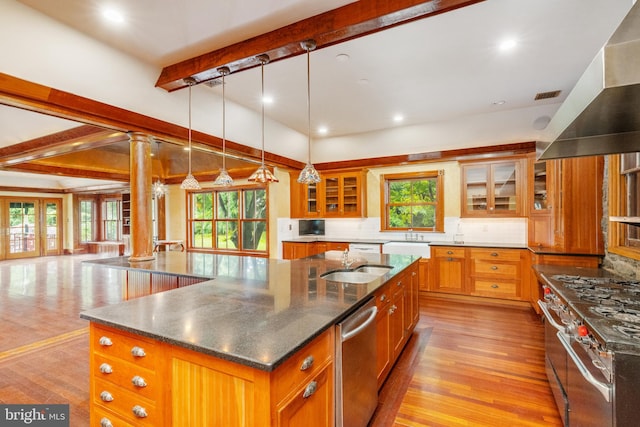 kitchen with decorative light fixtures, decorative columns, a kitchen island with sink, and beamed ceiling