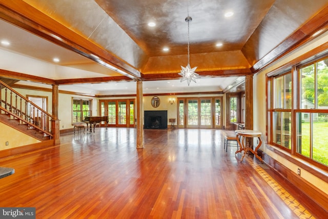 unfurnished living room with a notable chandelier, a wealth of natural light, and wood-type flooring