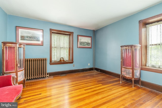 sitting room with a healthy amount of sunlight, radiator, and light wood-type flooring