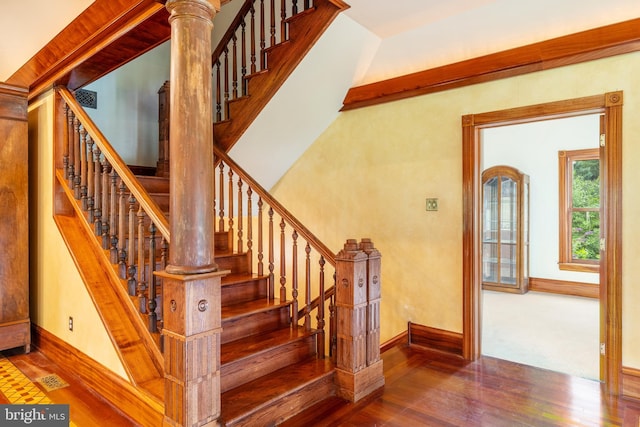 stairway featuring decorative columns and dark hardwood / wood-style floors