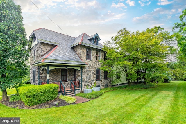 view of front of home featuring a front yard, central AC, and covered porch