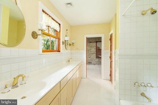 bathroom with dual sinks, backsplash, tile walls, and large vanity