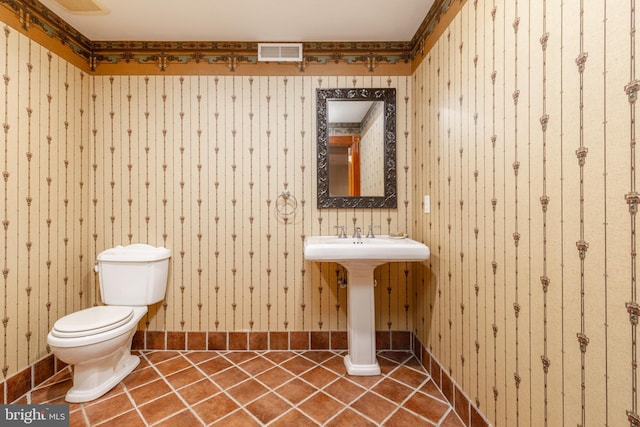 bathroom featuring wooden walls, toilet, and tile flooring