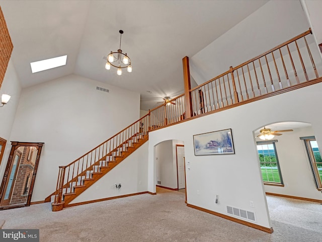 interior space featuring high vaulted ceiling, ceiling fan with notable chandelier, and carpet floors