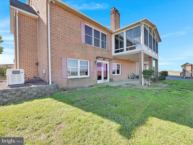 rear view of house featuring a patio, a storage unit, a sunroom, and a lawn