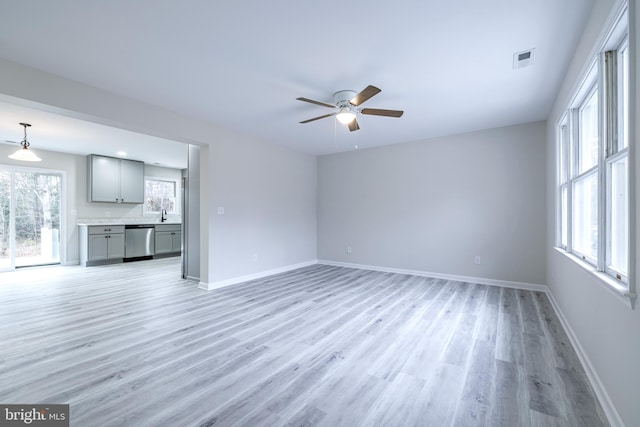 unfurnished living room featuring light hardwood / wood-style flooring, sink, and ceiling fan