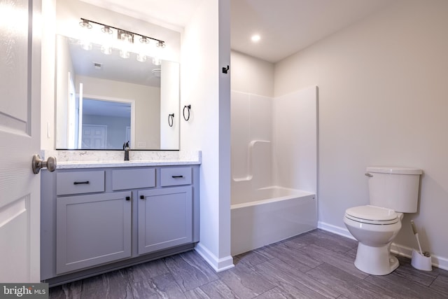 full bathroom with vanity, hardwood / wood-style floors, washtub / shower combination, and toilet