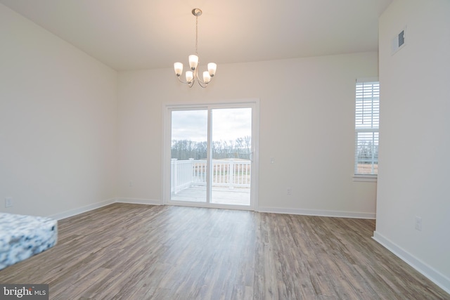 empty room featuring a chandelier and wood-type flooring