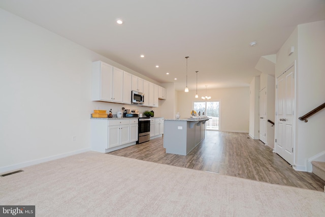 kitchen with white cabinets, appliances with stainless steel finishes, a center island, and pendant lighting