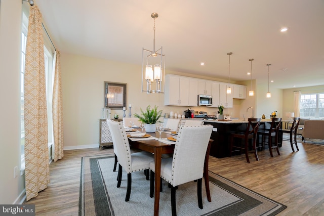 dining space with a notable chandelier, sink, and light wood-type flooring