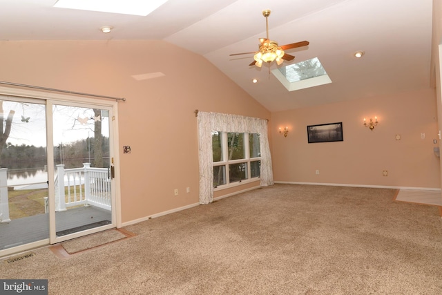 unfurnished living room featuring high vaulted ceiling, a water view, a skylight, ceiling fan, and carpet floors