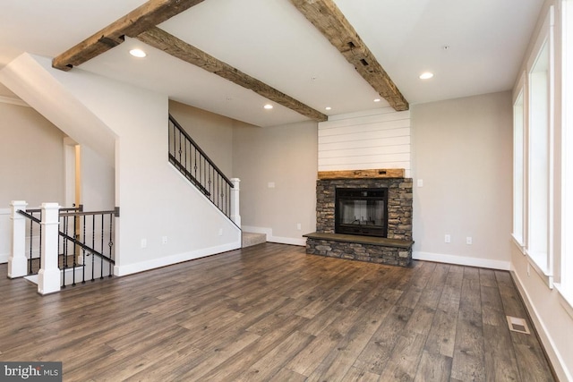 unfurnished living room with beamed ceiling, dark hardwood / wood-style floors, and a stone fireplace