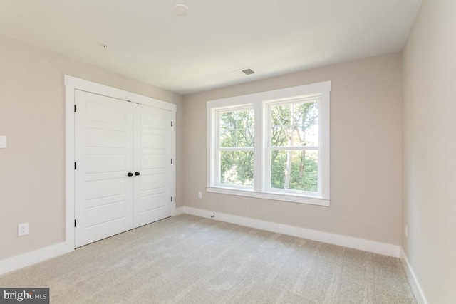 unfurnished bedroom with light carpet and a closet