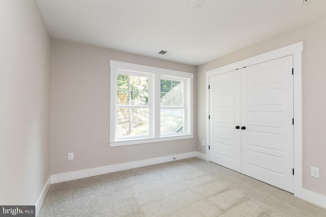 unfurnished bedroom with light colored carpet and a closet