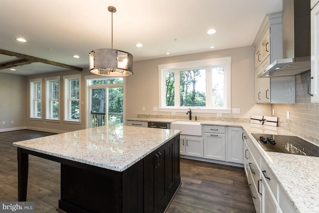 kitchen with wall chimney exhaust hood, sink, dark hardwood / wood-style floors, a kitchen island, and hanging light fixtures