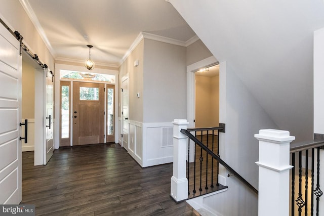 foyer with a barn door, ornamental molding, and dark wood-type flooring