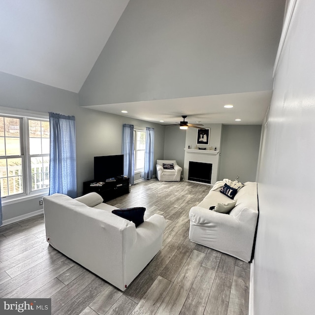 living room featuring high vaulted ceiling, light hardwood / wood-style floors, ceiling fan, and a healthy amount of sunlight