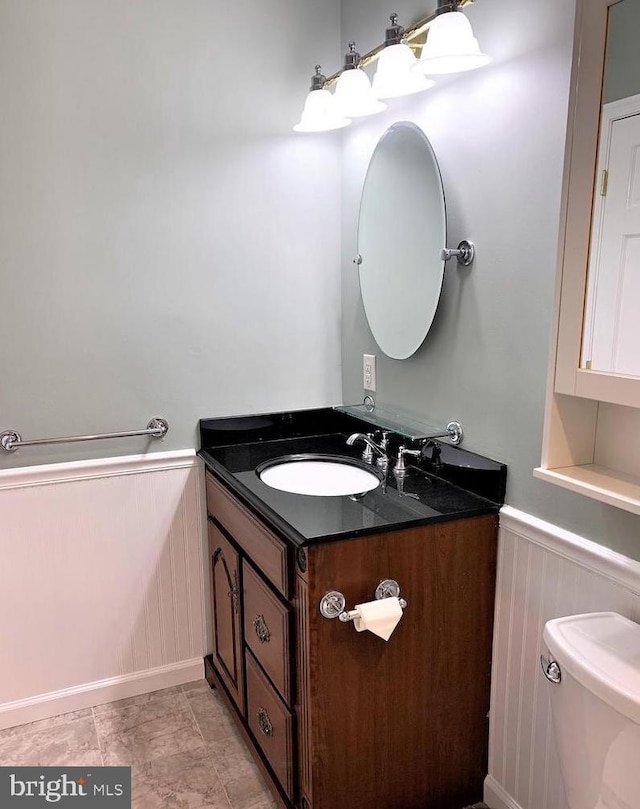 8067 Croom Rd, Upper Marlboro, MD 20772 - bathroom with a wainscoted wall, toilet, vanity, and a decorative wall