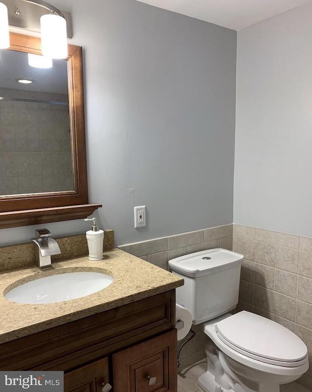 8067 Croom Rd, Upper Marlboro, MD 20772 - bathroom featuring toilet, vanity, tile walls, and wainscoting
