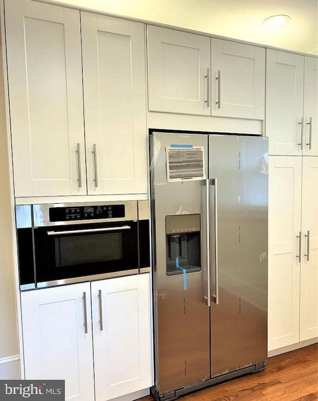 8067 Croom Rd, Upper Marlboro, MD 20772 - kitchen featuring appliances with stainless steel finishes, wood finished floors, and white cabinets