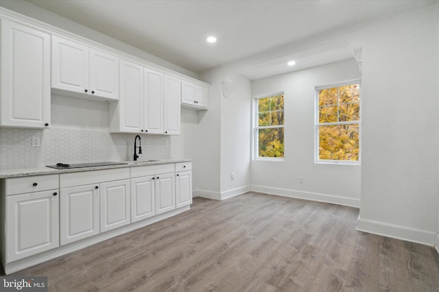 kitchen featuring backsplash, light hardwood / wood-style flooring, white cabinetry, and sink