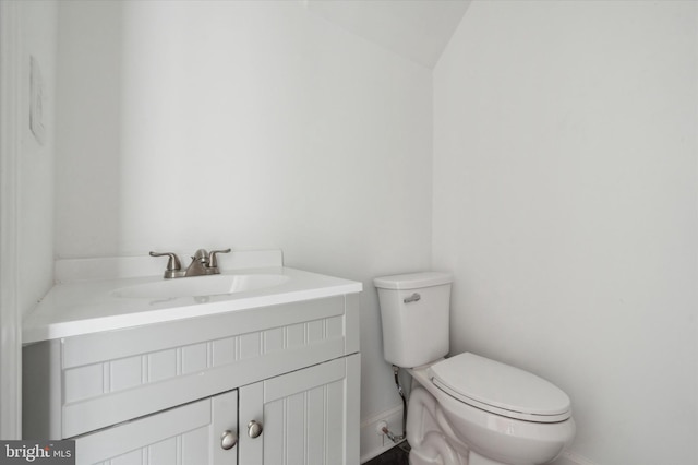 bathroom featuring toilet, vanity, and vaulted ceiling