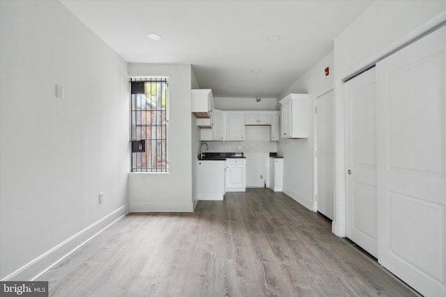 kitchen with backsplash, sink, white cabinets, and light hardwood / wood-style flooring