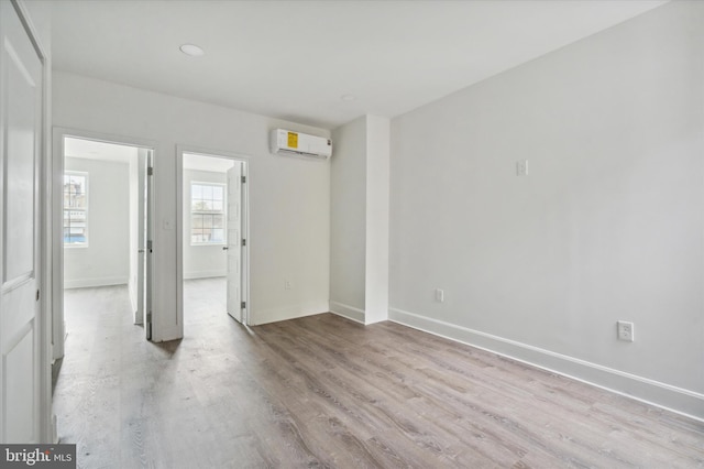 unfurnished bedroom featuring a wall mounted air conditioner and light hardwood / wood-style flooring