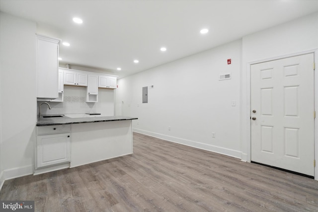 kitchen featuring backsplash, white cabinetry, sink, and hardwood / wood-style floors