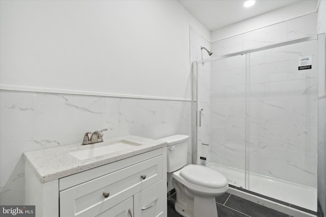 bathroom featuring toilet, a shower with shower door, vanity, tile walls, and tile flooring