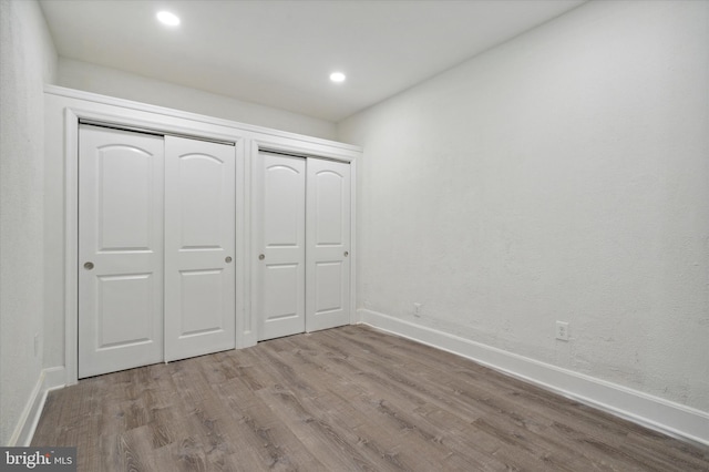 unfurnished bedroom with wood-type flooring and multiple closets