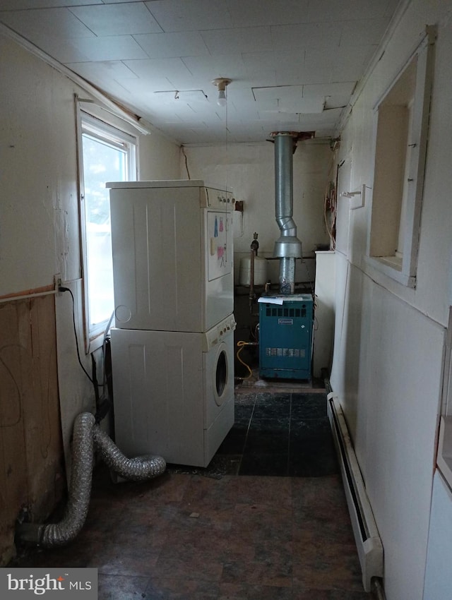 interior space featuring stacked washer / dryer, dark tile floors, and a baseboard heating unit