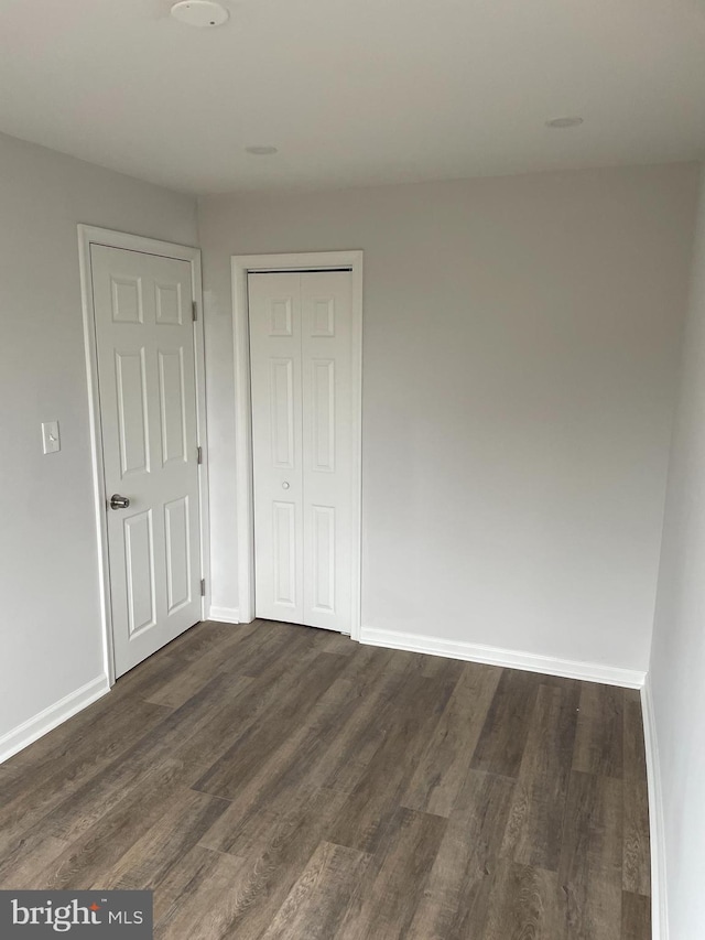 unfurnished bedroom with a closet and dark wood-type flooring